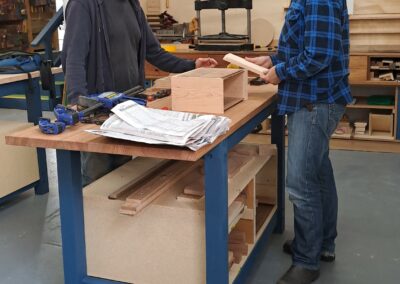 Tutor advising a woodworking student on some joinery