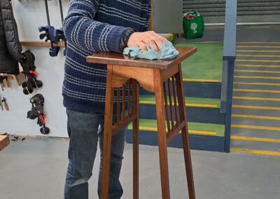 Furniture Restoration student rubbing back the finish on his timber plant stand